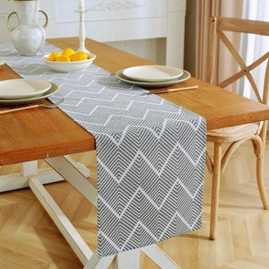 Detail view of gray wave pattern cotton linen table runner on a wooden dining table