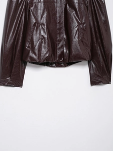 Detail of burgundy faux leather bomber jacket showing stitching and hemline texture