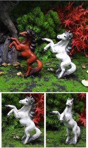 Detail of white horse figurine jumping on mossy stones in miniature garden landscape