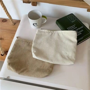 Corduroy makeup bags in khaki and cream white showing ribbed texture and metal zipper