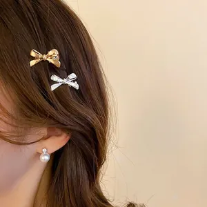 Elegant gold and silver bow hair clips and pearl drop earrings worn by a model