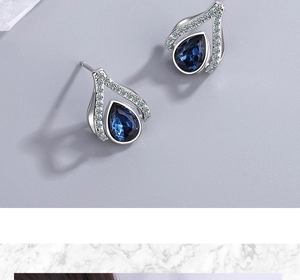 Macro shot of silver stud earrings with teardrop blue crystals and micro-pave cubic zirconia