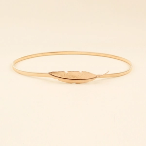 Detail of a gold feather buckle on a flexible metal spring waist chain for dresses