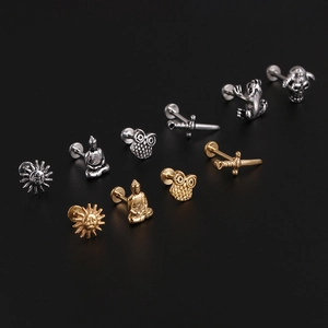 Detail of assorted gold and silver labret studs featuring frog and skull designs