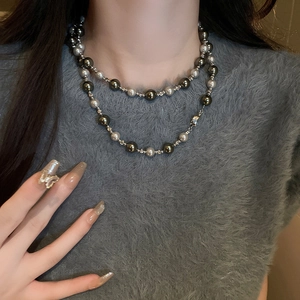 Gros plan d'un collier double épaisseur avec perles noires et blanches sur un mannequin