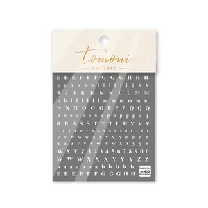 Dettaglio di adesivi per unghie bianchi con lettere maiuscole, minuscole e numeri per nail art