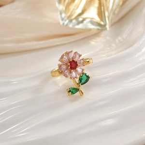 Close-up of golden floral ring with colorful zircon petals on white porcelain base