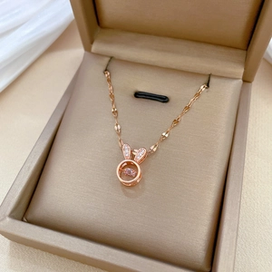 Elegant rose gold rabbit pendant necklace with pink gemstone in a beige jewelry box