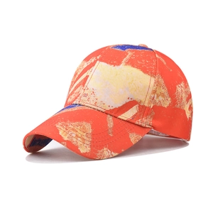 Close-up of a red cotton baseball cap with artistic yellow and blue graffiti print
