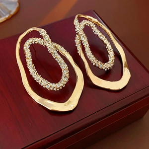 Detailed close-up of gold-plated oval stud earrings with glittering cubic zirconia pavé