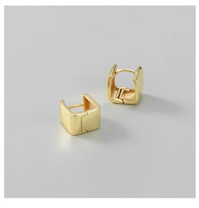 Macro shot of polished gold square huggie earrings with a geometric reflective finish