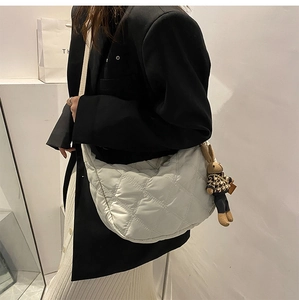 Close-up of white quilted half-moon bag with cute rabbit charm and metal hardware