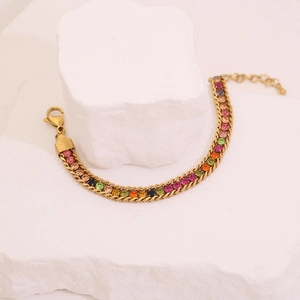 Detail of gold chain bracelet set with multicolored round gemstones on stone base