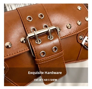 Détail de boucles argentées et de rivets sur un sac baguette en cuir marron caramel