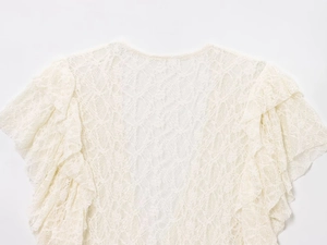 Gros plan d'une chemise en dentelle crème montrant la texture fine des mailles florales