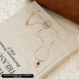 Détail d'un collier vintage œil de tigre doré posé sur un livre avec dimensions