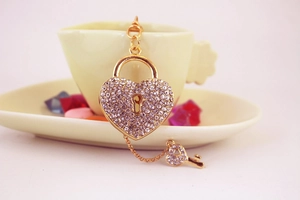 Close-up of heart-shaped lock and key keychain with sparkling rhinestones on ceramic cup