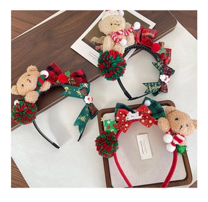 Christmas plush bear headband set with red green bows and pom-poms on wooden base