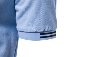 Détail de la manche d'un polo en piqué bleu clair avec double rayure bleu marine sur le bord