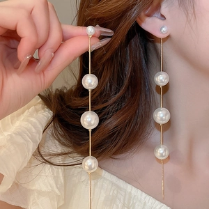 Close-up of white pearls on fine gold chains for an elegant drop earring look