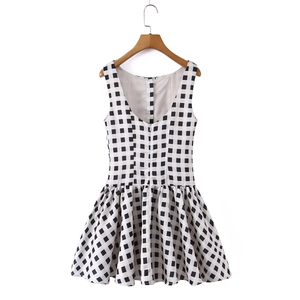 Detail of a sleeveless V-neck plaid dress with button accents and a pleated skirt