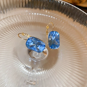 Close-up of deep blue oval-cut gemstones on gold-plated French leverback earrings