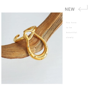 Detail of a gold horseshoe-shaped open ring with cubic zirconia on a wooden stand