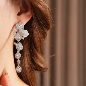 Gros plan de boucles d'oreilles pendantes en argent avec fleurs et feuilles en zircon