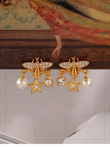Detailed view of luxury bee earring with sparkling crystals and a white faux pearl charm
