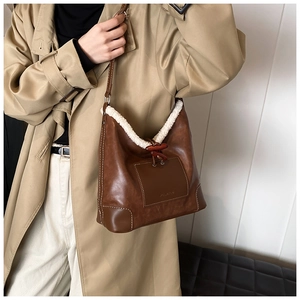 Detail of vintage brown leather tote with white faux shearling trim and wooden toggle button