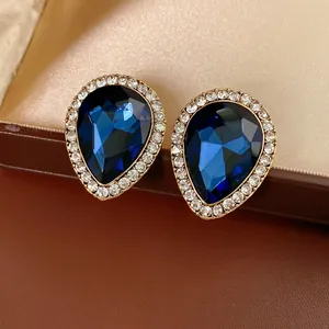 Vintage teardrop earrings with blue crystals and gold trim on leather box