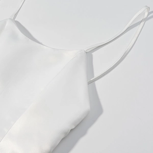 Detail of white satin dress featuring delicate spaghetti straps and premium cowl neckline