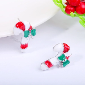 Macro detail of Christmas candy cane earrings with red white enamel and green bow