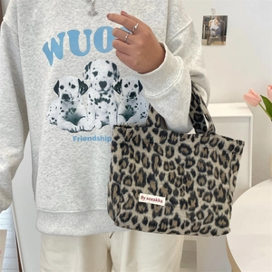 Close-up of plush leopard print handbag with brand label and soft fabric texture