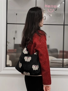 Detail of black jacquard shoulder bag with white butterfly embroidery and red gems