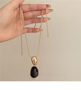 Close-up of vintage resin oval pendant with gold snake chain being held by hand