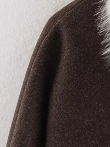 Detailed view of dark brown wool coat shoulder with premium white faux fur collar trim