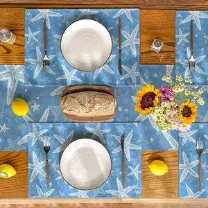 Detail of blue beach table runner and placemat set with white starfish print on wood