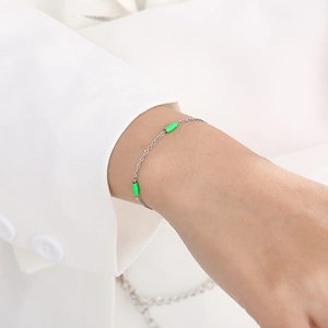 Gros plan du bracelet chaîne argentée avec des perles cylindriques en émail vert néon