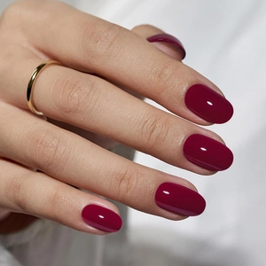 Uñas postizas almendradas rojo oscuro con acabado brillante y detalle de anillo dorado