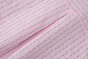 Gros plan sur la texture du tissu à rayures roses avec détails de couture soignés
