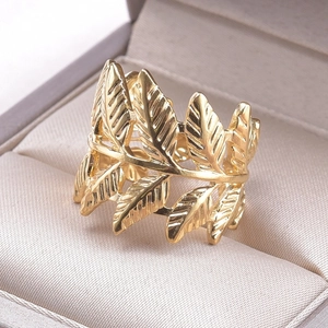 Macro detail of golden leaf-shaped ring showing intricate texture on jewelry box