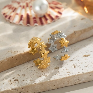 Minimalist gold and silver star-shaped open rings displayed on a stone surface