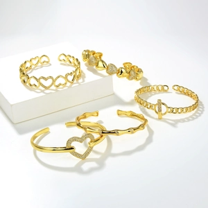 Set di quattro bracciali rigidi a cuore dorati con zirconi su espositore bianco