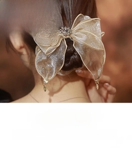 Close-up of champagne gold pearlescent silk bow hair tie with rhinestone center detail