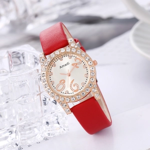 Détail d'une montre femme avec lunette en strass or rose et bracelet en cuir rouge