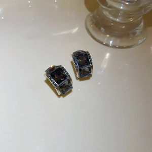 Macro shot of silver stud earrings featuring square dark grey crystals and micro-pave stones