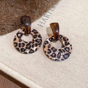 Detailed macro view of vintage leopard print resin hoop earrings on a soft fabric texture