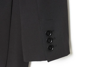 Détail du poignet d'une veste de costume noire avec trois boutons circulaires