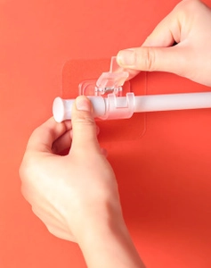 Détail du support adhésif transparent pour tiges télescopiques sur fond rouge vif